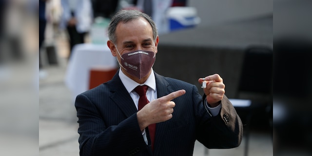 Mexico's Coronavirus Response Chief Hugo Lopez-Gatel points to the vial of the COVID-19 vaccine as it was first used by health workers at the General Hospital in Mexico City early Thursday, December 24, 2020 (AP Photo / Eduardo Verdugo )